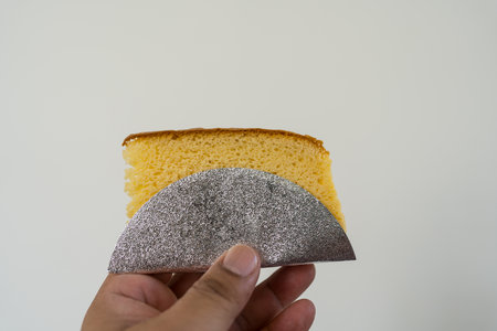 Hand holding a piece sponge cake baked. Close up