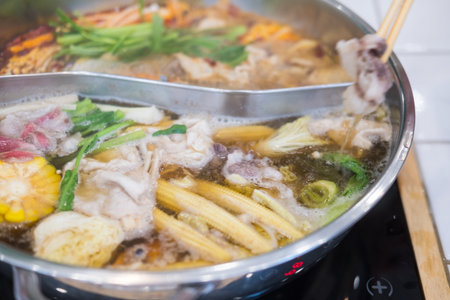 Someone using chopsticks to pick up food from a hotpot soup.の写真素材