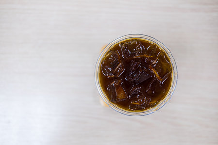 A top view of a glass filled with iced black coffee, glistening with ice cubes