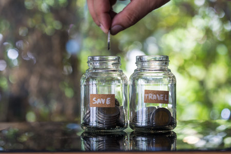 Hand putting coin in jar for saving and investment concept. Try to put a coin into a glass jug for...