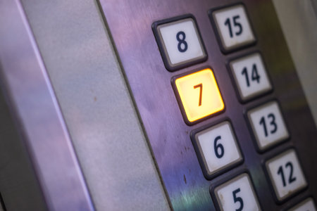 The seventh floor button in an elevator, illuminated with orange light on a gray metallic panel