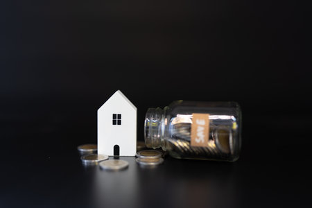 Home model and money in jar glass. Saving money to invest in house or property in the future....