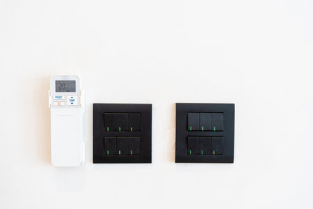 Air conditioner remote control and panel electrical switch on wall.