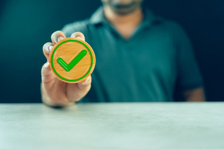 Hand holding a wood block with check mark icon. Checklist Survey and assessment concept signifying...