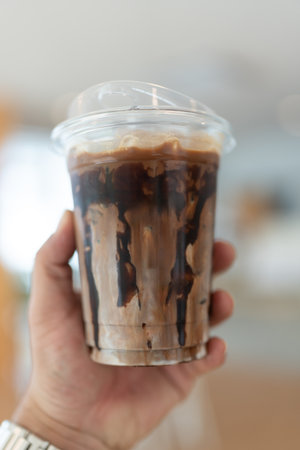 Iced mocha coffee with chocolate drizzle on man handの写真素材