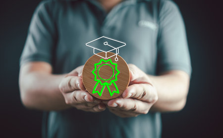 Man holding a wooden circle showing a graduation hat. Knowledge creative thinking, E-learning graduate certificate program concept. Graduate certificate online concept.の写真素材