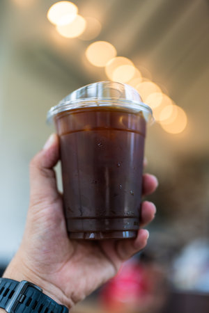 Man hand holding iced black coffee or americano coffee in coffee shop.の写真素材