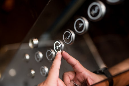 Hands and pressing button in elevator for transportation in building. Elevator control panel in small buildingの写真素材