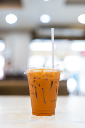 Thai milk tea served in a cup placed on tableの写真素材