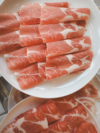 Raw sliced pork for Sukiyaki and Shabu on white dish, top view