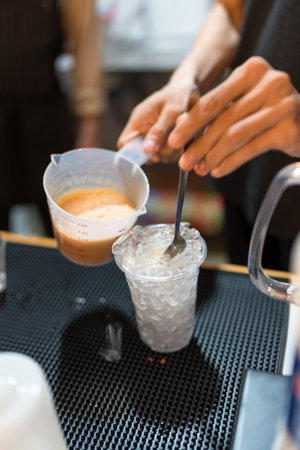Man making a cup of Thai milk tea in bar counter at coffee shop cafeの写真素材