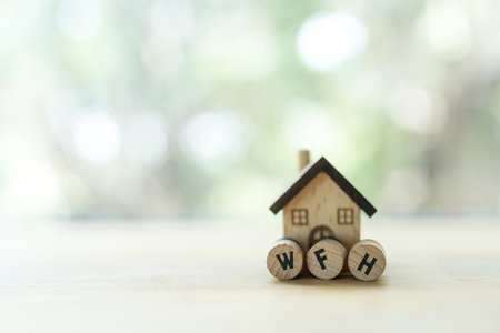 WFH acronym of work from home is made from wooden blocks placed in front of wood home. The concept of self-detention at home a precaution against virus outbreaks. Staying at home during an emergencyの写真素材