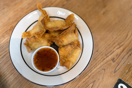 Crispy fried dumpling paste stuffed chop pork dipping sweet chili sauce on plate