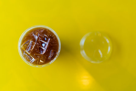 A plastic cup of ice black coffee or ice americano on a yellow background.の写真素材