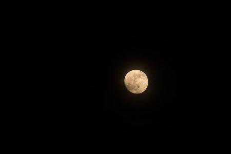 Full, golden-hued moon against a black backdrop in night