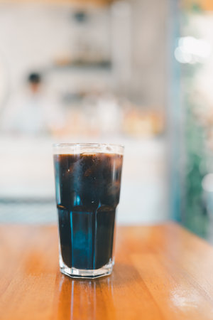 A glass filled with iced black coffee on wood table. Refreshing drinkの写真素材
