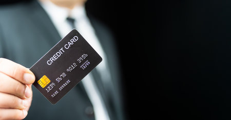 Businessman in black suit holding a black credit card, privileges high level personal payment purchase luxury class show membershipの写真素材
