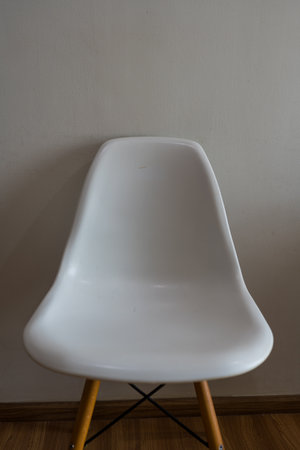 Modern white plastic chair with wooden legs. The chair features a molded seat and sleek legsの写真素材