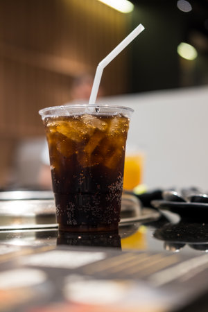 Refreshing soft drink in plastic cup with white straw. Close up