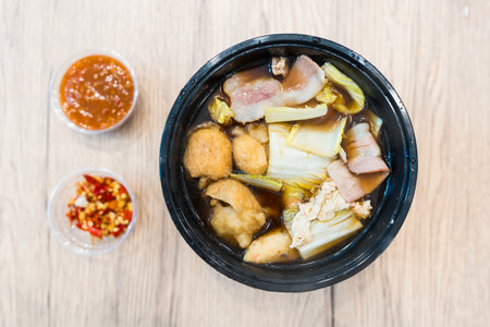 Vegetable and pork sukiyaki in soup on black bowl.