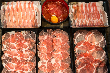 A fresh raw beef and pork sliced with rich fat marbling on an elegant black premium plate, showcasing luxury meat texture for gourmet, culinary, and fine dining concepts.の写真素材