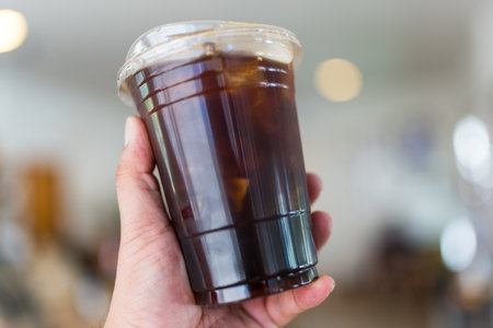 Man hand holding iced black coffee or americano coffee in plastic cup