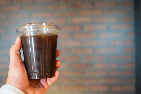 Close up hand holding Iced black coffee in take away plastic cup