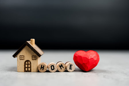 Wooden house and text with HOME next to red heart. Love home symbol, insurance concept. Home sweet home.