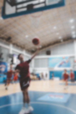 Blur background man dunking ball in hoop while playing basketball in gymnasium