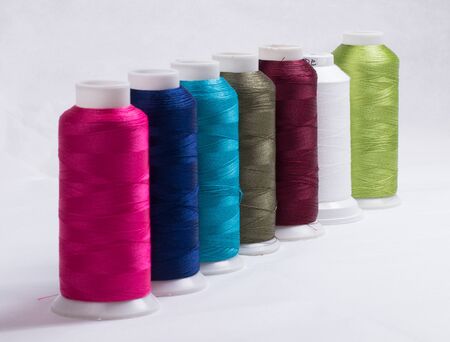 Spools of spools of thread in various colors against a white background