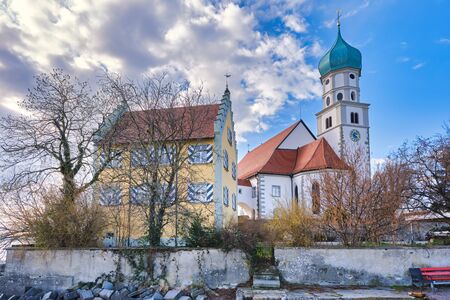 Church and house under cloudy skies, bare treesの写真素材