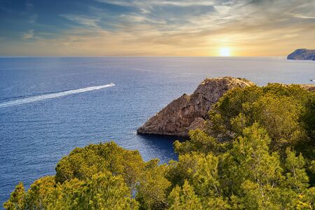 Motorboat drives towards the coast along the sunset, blue sky, Mallorca, Spain
