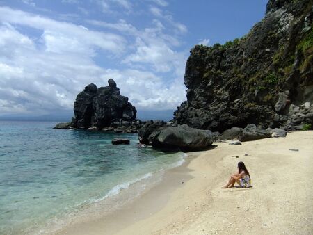Young woman sitting on a tropical beach in dressの写真素材