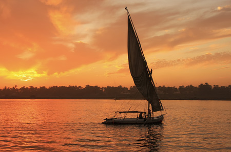 Felucca boat sailing on the Nile river at sunset, Luxor, Egypt