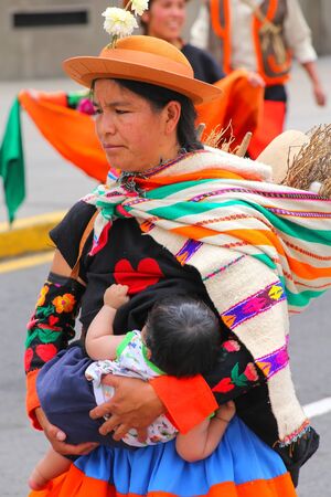 Local woman with a baby walking during Festival of the Virgin de la Candelaria in Lima, Peru. The core of the festival is dancing and music performed by different dance schools.のeditorial素材