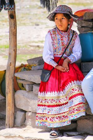 Girl in traditional dress sitting at the market in Maca village in Colca Canyon, Peru. Maca is one of the three main tourist towns of the Colca Canyon.のeditorial素材