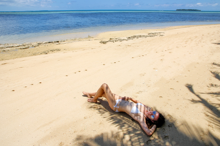 Young woman in bikini lying on the beach on Makaha'a island near Tongatapu island in Tonga. Kindom of Tonga is an archipelago comprised of 169 islandsの写真素材