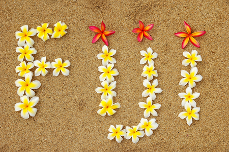 Word Fiji written on a beach with plumeria flowers - travel conceptの写真素材