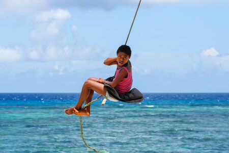 Local girl swinging on a rope swing in Lavena village on Taveuni Island, Fiji. Taveuni is the third largest island in Fiji.のeditorial素材