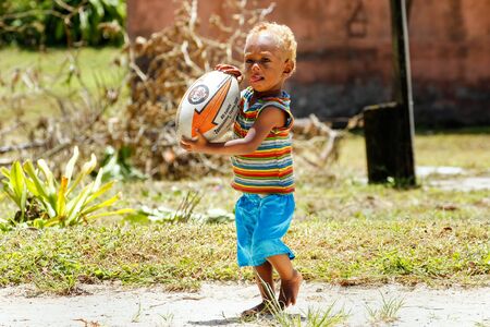 Young boy playing with rugby ball in Lavena village, Taveuni Island, Fiji. Rugby is considered to be the national sport of the countryのeditorial素材