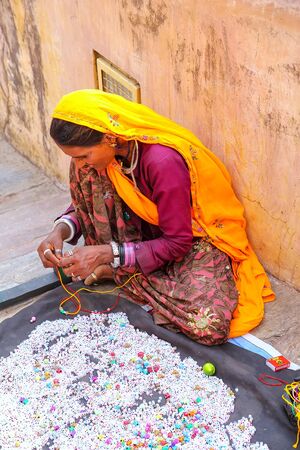Local woman making necklaces in Amber Fort near Jaipur, Rajasthan, India. Amber Fort is the main tourist attraction in the Jaipur area.のeditorial素材