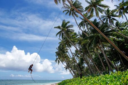 Local boy swinging on a rope swing in Lavena village, Taveuni Island, Fiji. Taveuni is the third largest island in Fiji.の写真素材