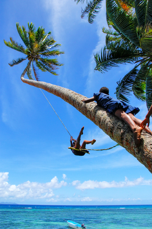 Local kids swinging on a rope swing in Lavena village, Taveuni Island, Fiji. Taveuni is the third largest island in Fiji.のeditorial素材