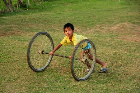 Local kid playing with wheels in Vang Vieng, Laos. Vang Vieng is a tourist-oriented town in Vientiane Province.のeditorial素材