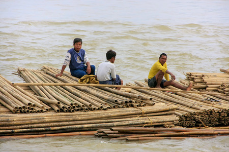 Local men floating on a bamboo raft down Ayeyarwady river near Mandalay, Myanmar. Ayeyarwady river is the largest river in Myanmar.のeditorial素材