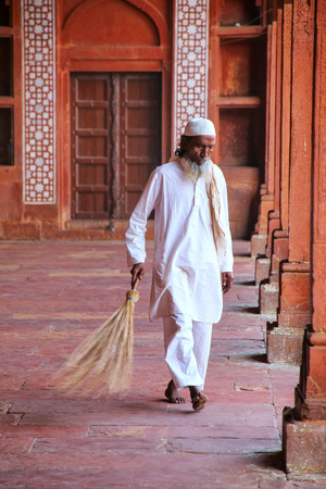 Worker sweeping courtyard of Jama Masjid in Fatehpur Sikri, Uttar Pradesh, India. The mosque was built in 1648 by Emperor Shah Jahan and dedicated to his daughter  Jahanara Begumのeditorial素材