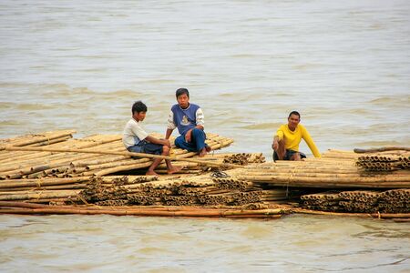 Local men floating on a bamboo raft down Ayeyarwady river near Mandalay, Myanmar. Ayeyarwady river is the largest river in Myanmar.のeditorial素材