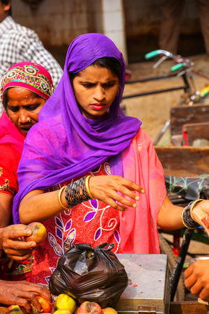Local woman buying apples at the street market in Fatehpur Sikri, Uttar Pradesh, India. The city was founded in 1569 by the Mughal Emperor Akbar, and served as the capital of the Mughal Empire from 1571 to 1585のeditorial素材