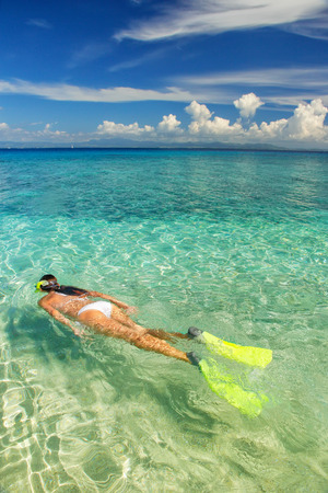 Young woman snorkeling in clear shallow water near tropical islandの写真素材