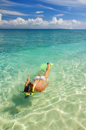 Young woman snorkeling in clear shallow water near tropical islandの写真素材
